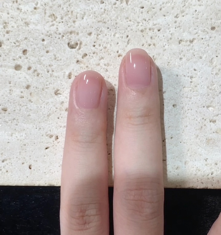 Un pinceau à ongles affinant soigneusement les bords et le bout dun ongle peint en rose