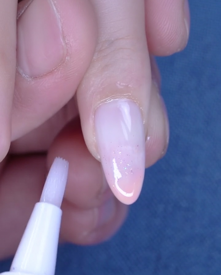 Un stylo à huile cuticule appliqué sur la peau hydratée autour dun ongle fraîchement manucuré.