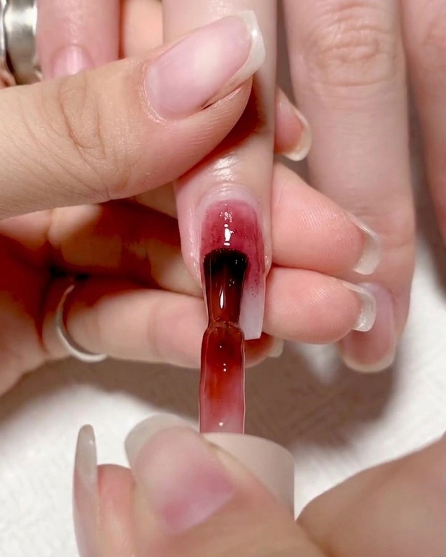 Application dun gel rouge vif sur la moitié gauche de longle.
