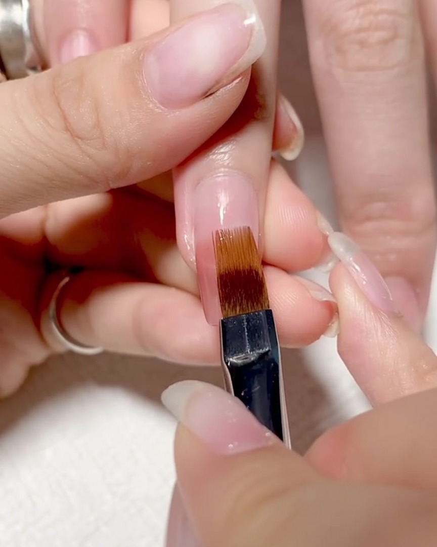 Un pinceau glissant doucement sur la surface de longle pour un ombré lisse.