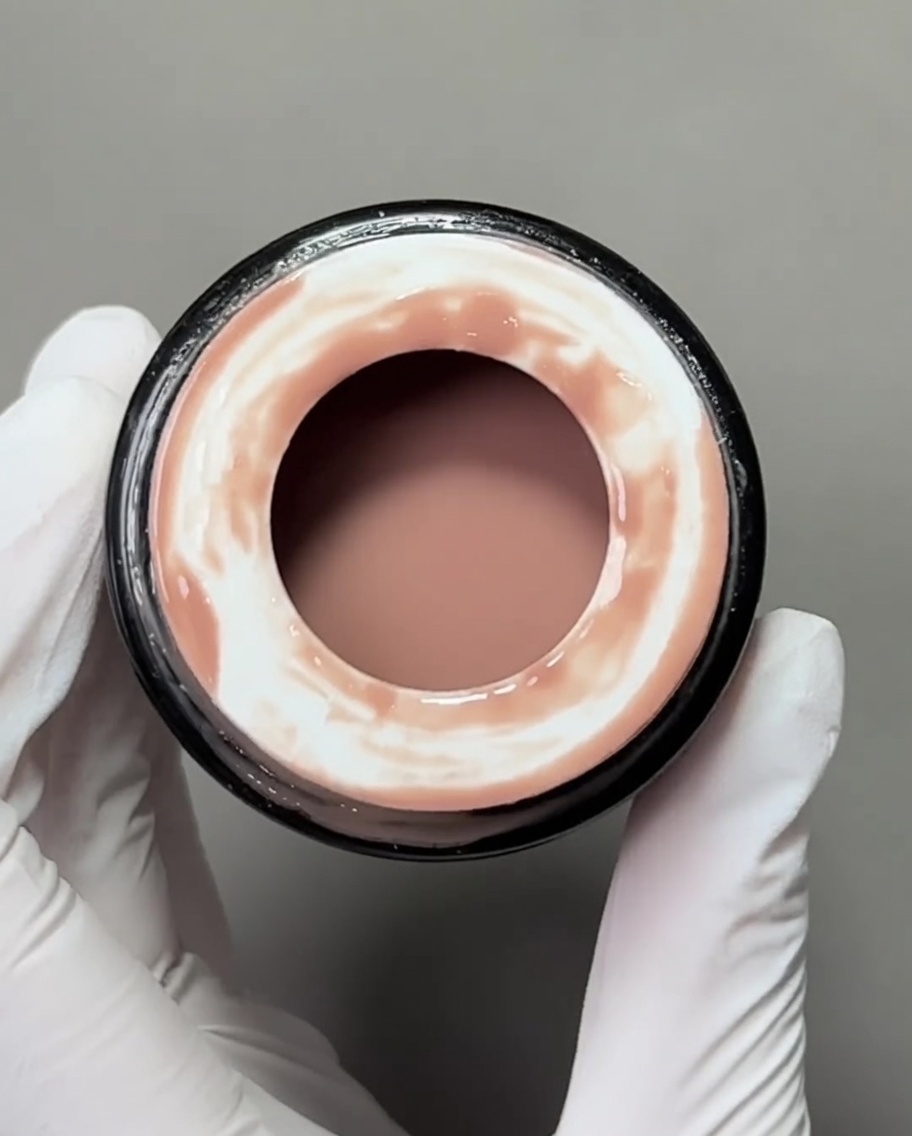 Gros plan sur un pinceau gel plat appliquant une base gel nude sur une capsule.
