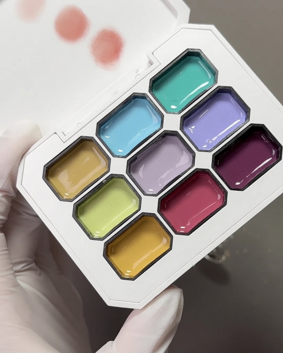 Une palette avec plusieurs gels de couleur pastel et une éponge à maquillage utilisée pour prélever les pigments.