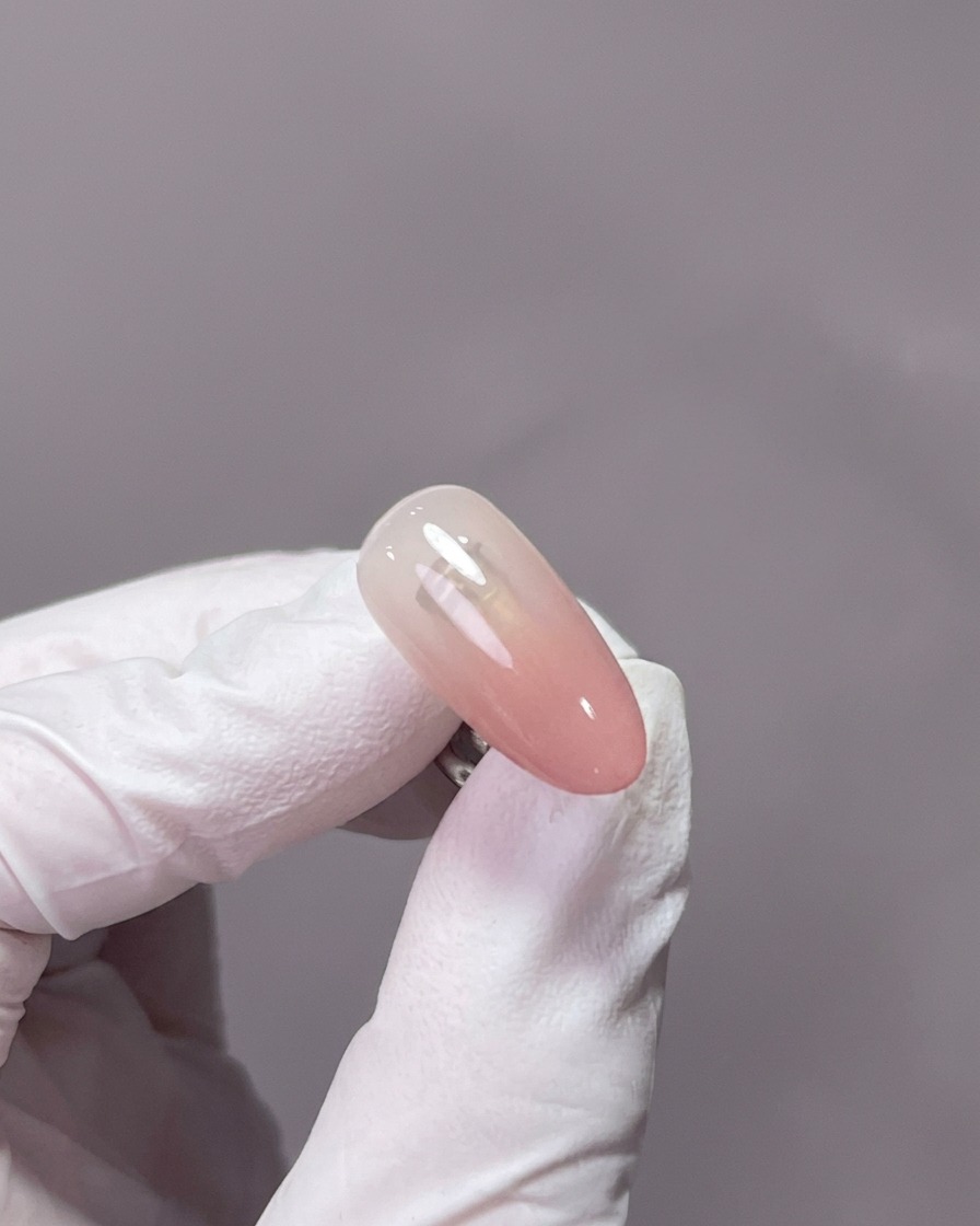 Gros plan dune main reposant à lintérieur dune lampe UV/LED professionnelle, les ongles recouverts de gel centrés sous la lumière.