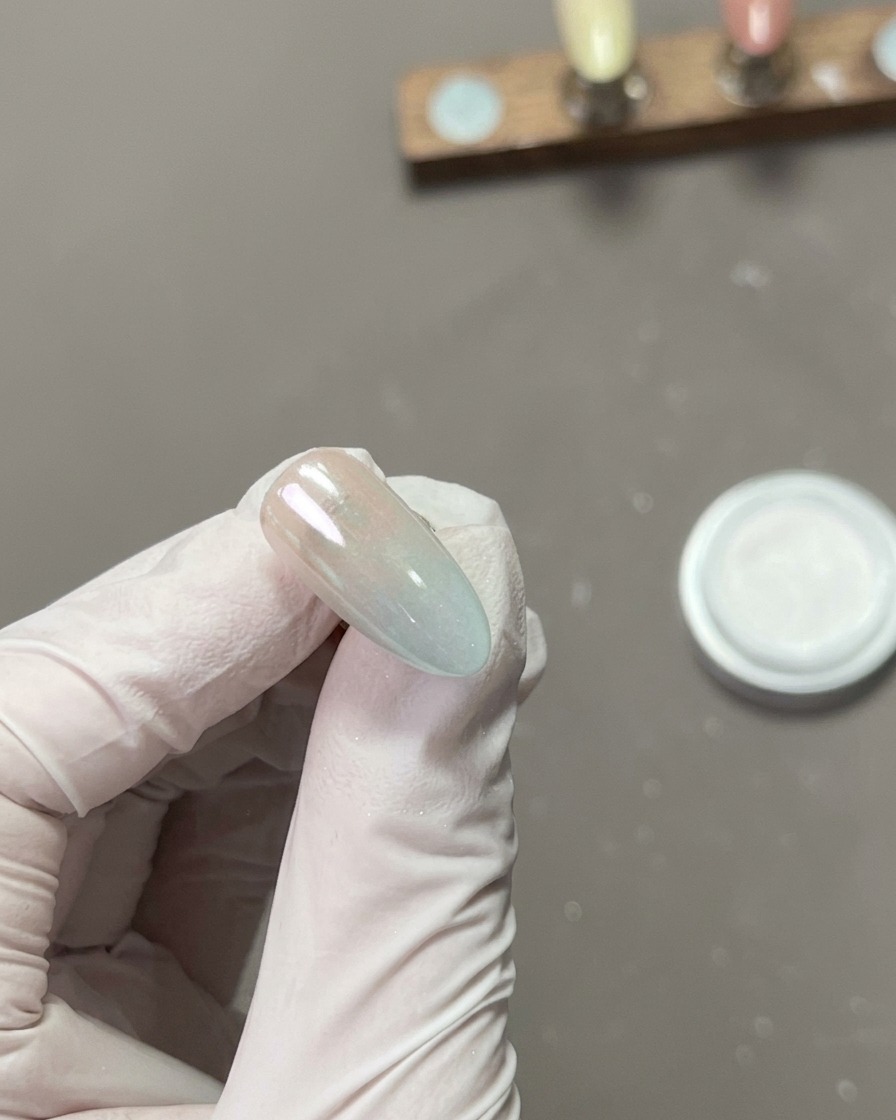 Gros plan dun doigt polissant la surface dun ongle chromé, créant un reflet miroir haute brillance.