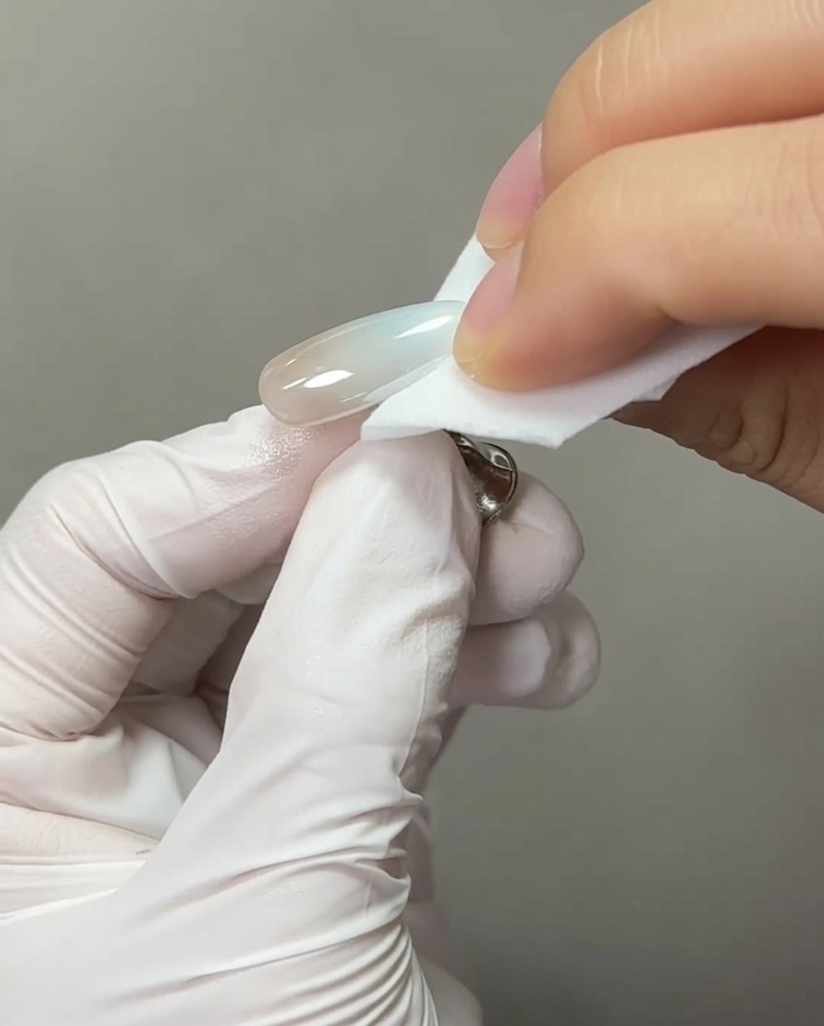 Gros plan dun pinceau à ongle appliquant une goutte de gel dextension transparent sur le bout dun ongle chromé.