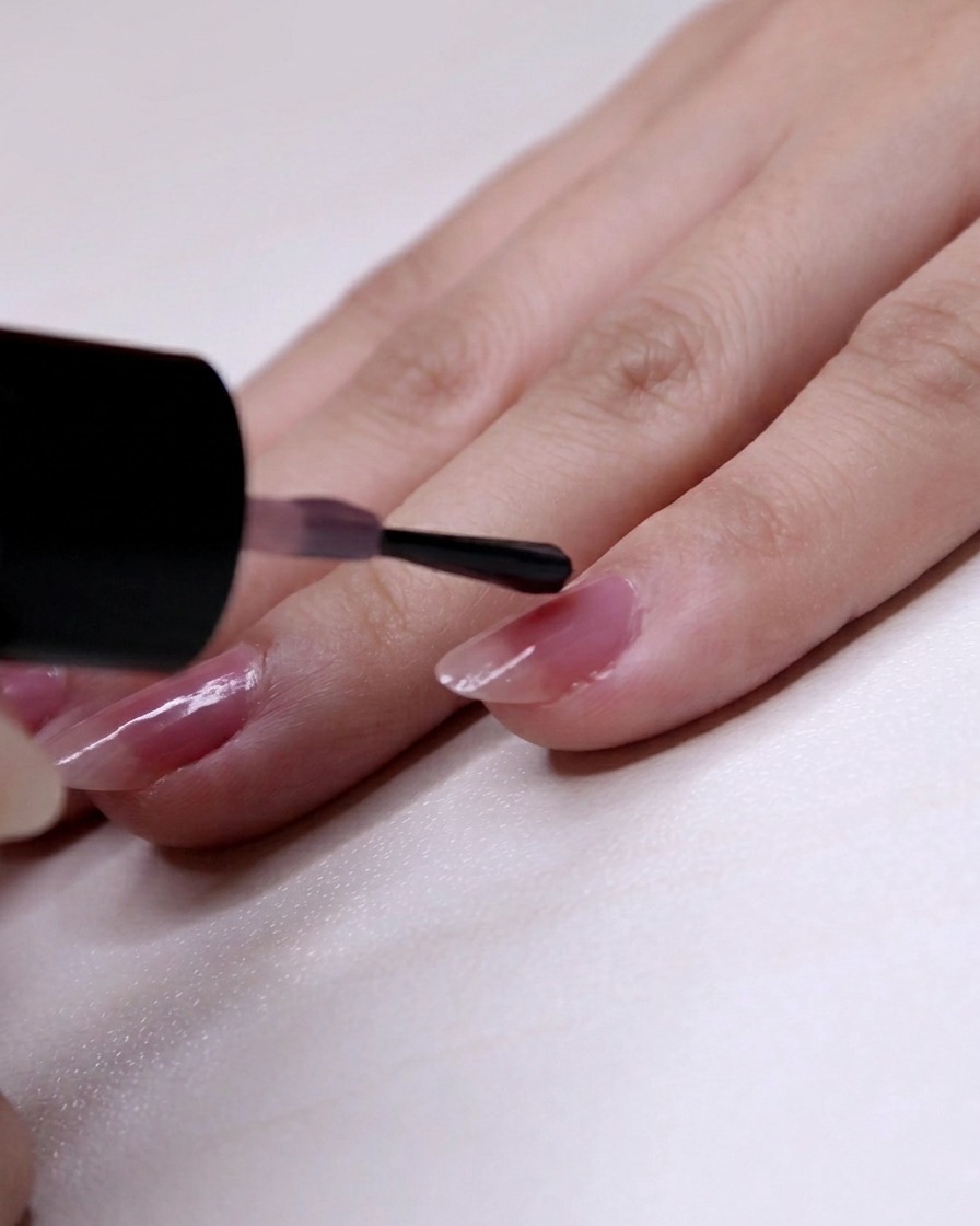 Le vernis rose appliqué à partir des deux tiers de la cuticule vers la pointe de longle du petit doigt.