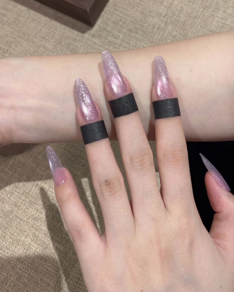 Un pinceau applique un vernis gel œil de chat aux reflets violets sur toute la surface de longle.