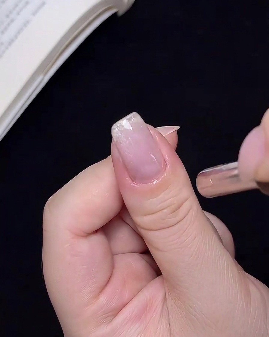 Gros plan dun aimant tenu près dun ongle, déplaçant les particules scintillantes.