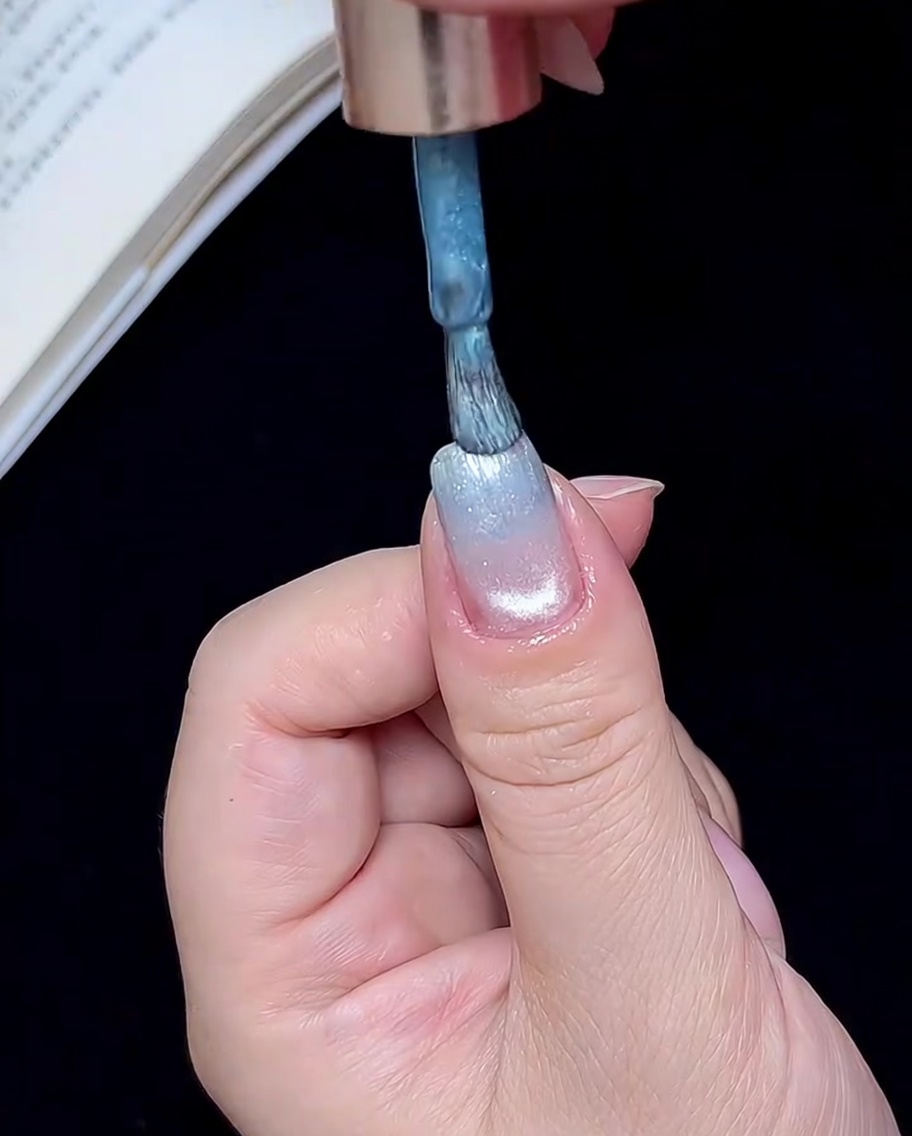 Un pinceau appliquant une petite quantité de gel bleu sur le bord libre de longle.