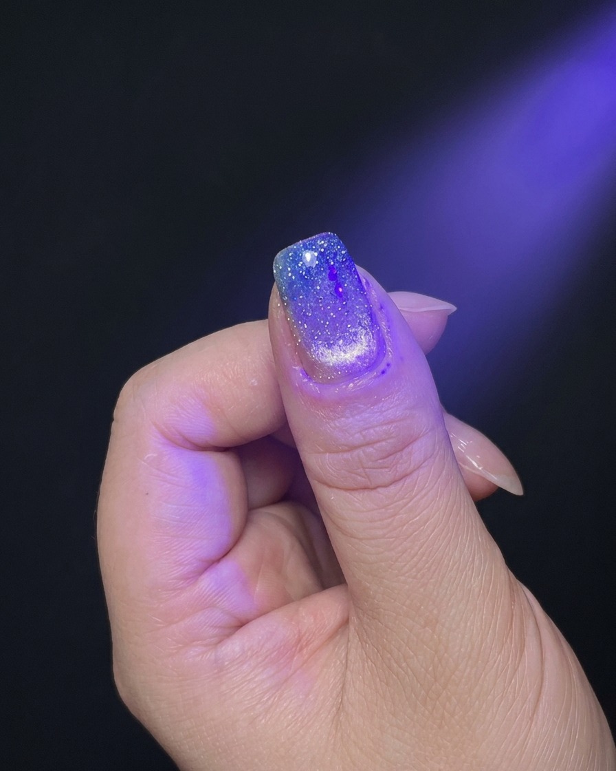 Une main positionnée sous la lumière violette dune lampe UV/LED.