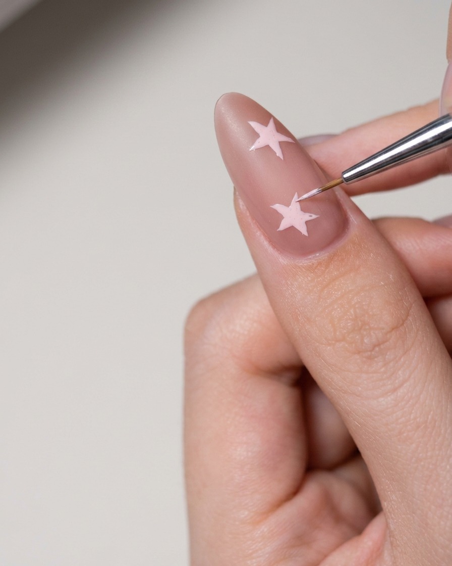 Un petit outil appliquant une pâte nail art blanche pour remplir la forme dune étoile sur longle.