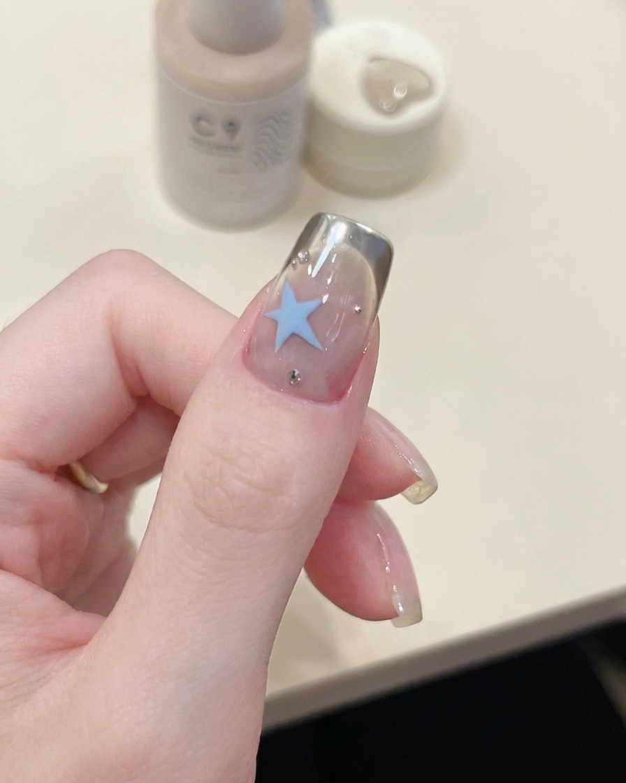 Une pince déposant un pochoir incurvé pour French manucure sur un ongle.