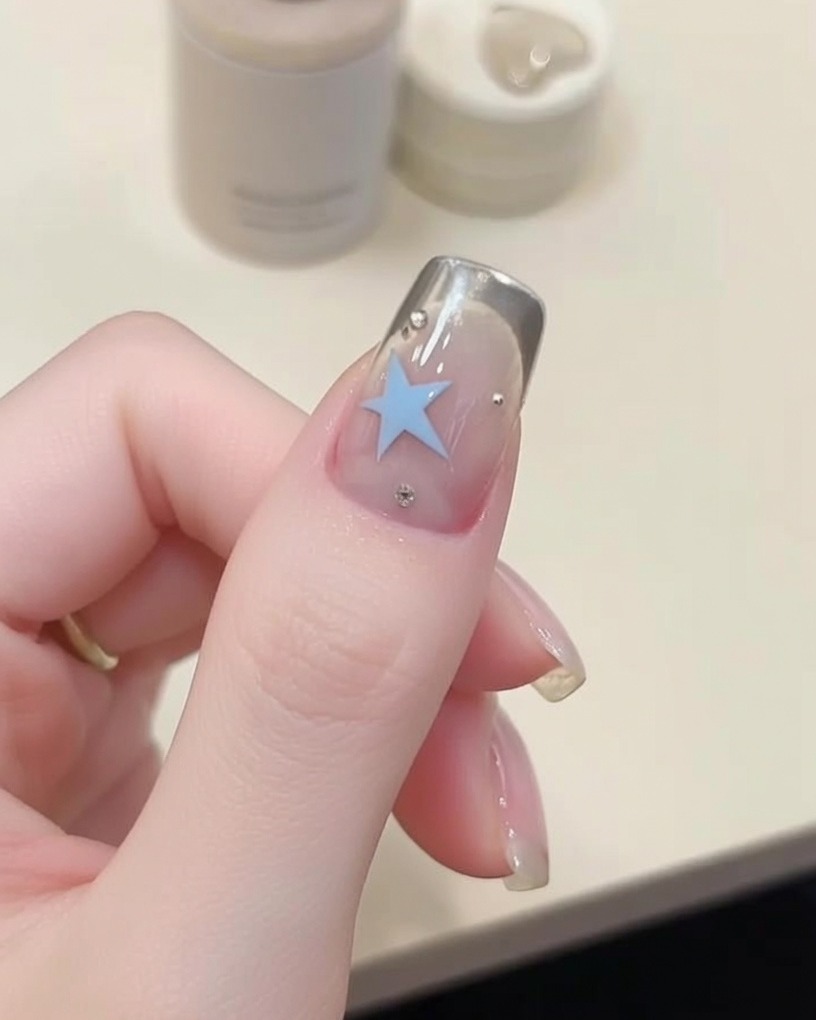 Gros plan dun pinceau fin dessinant une étoile avec du gel bleu.