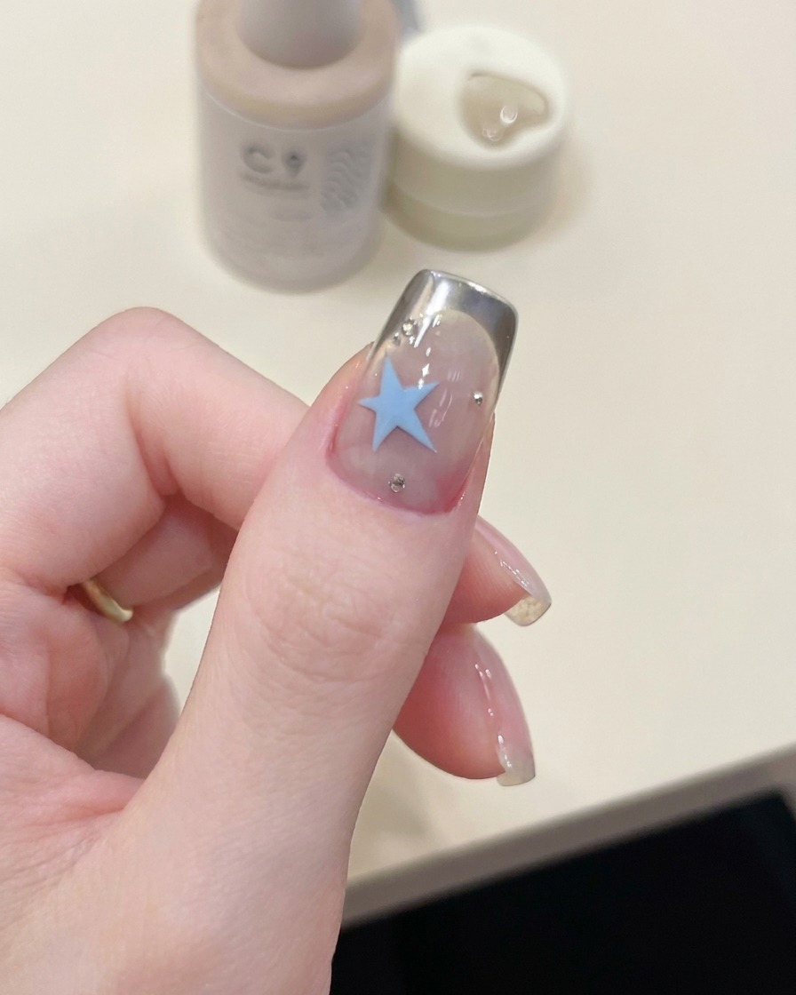 Un pinceau appliquant une couche de finition brillante sur le nail art terminé.