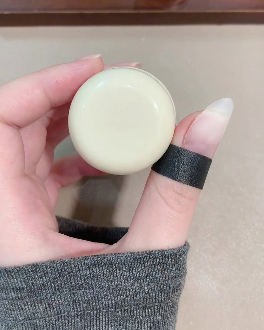 Un pinceau à gel appliquant un vernis œil de chat bleu transparent sur un ongle.