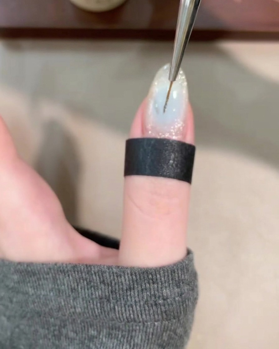 Gros plan dun pinceau fin traçant des lignes fluides sur une base de gel claire.
