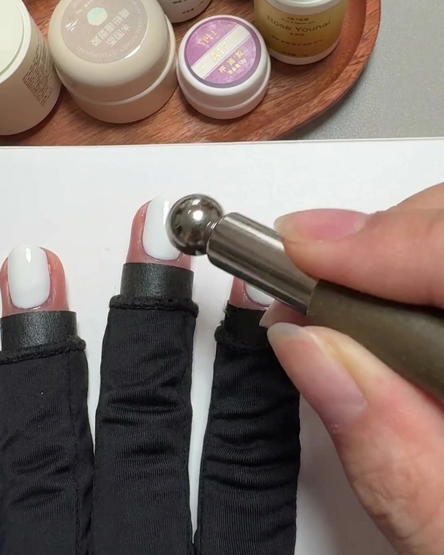 Gros plan dun outil aimanté cylindrique survolant un ongle verni pour créer leffet cat-eye.