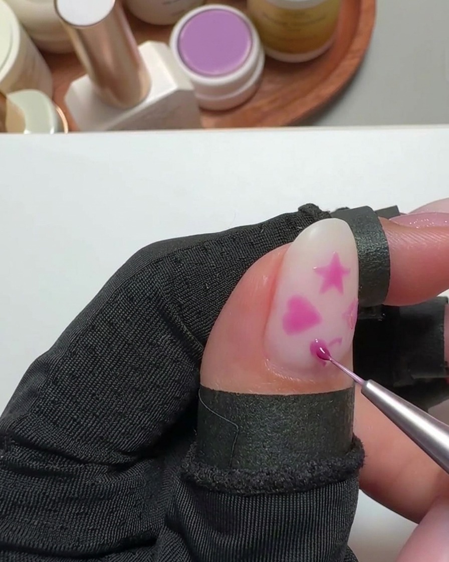 Un petit sticker de transfert placé sur un motif en forme de cœur sur un ongle.