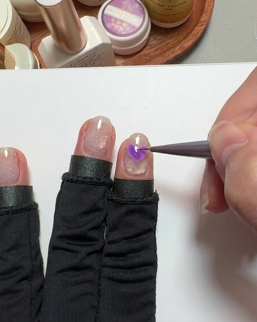 Un pinceau de précision remplissant une forme de cœur sur longle avec du gel rose.