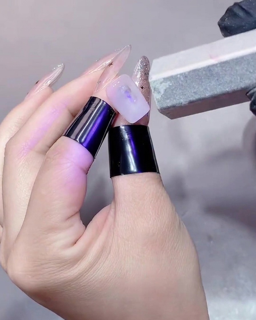 Gros plan dun ongle poli avec un bloc polissoir pour en lisser la surface.