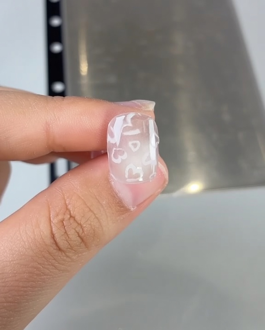 Gros plan dun pinceau appliquant du vernis gel rose sur un ongle.