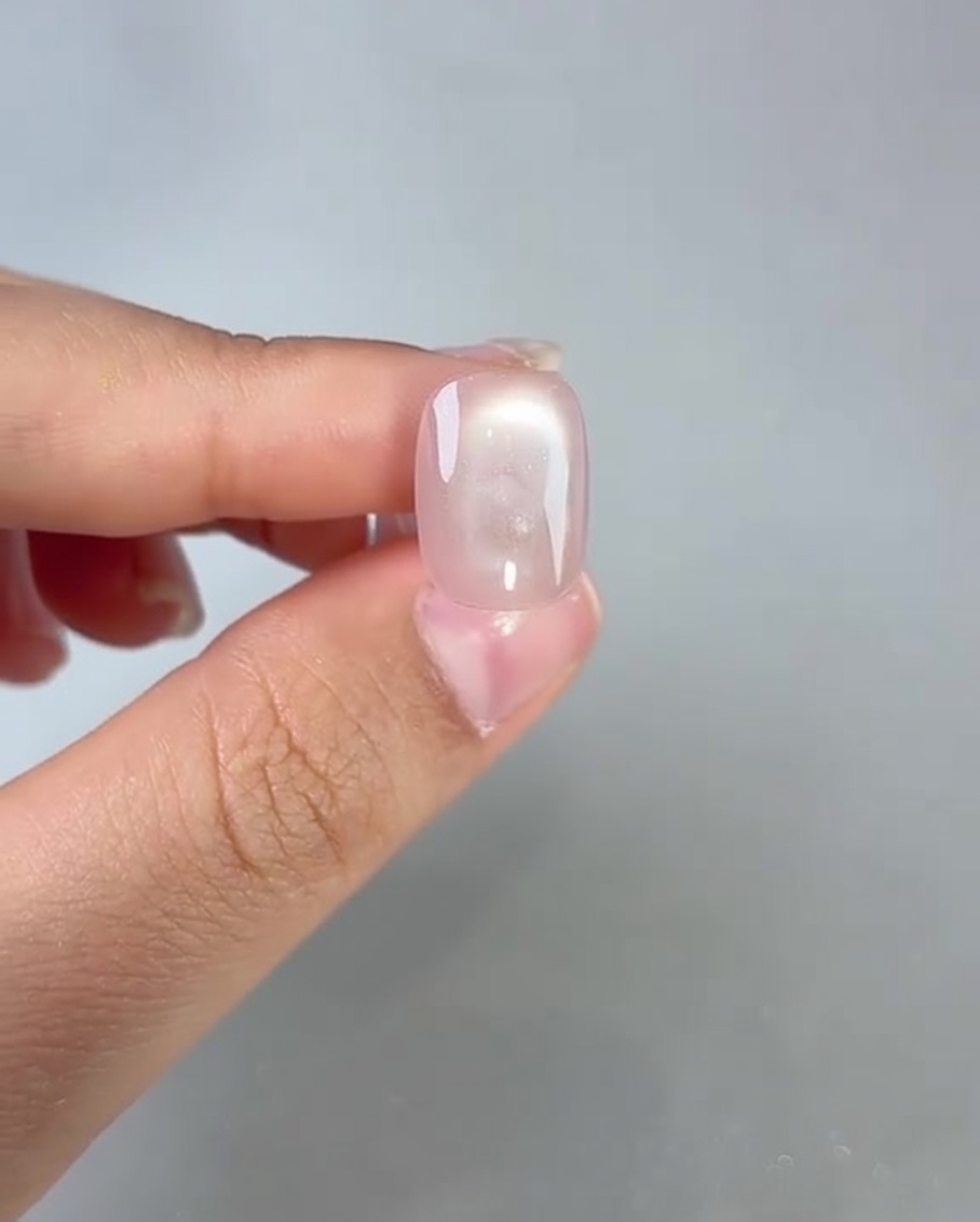 Pinceau appliquant un top coat transparent sur un ongle cat-eye catalysé.