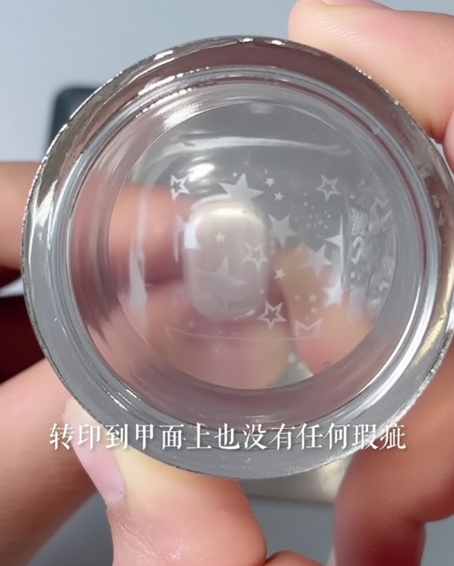 Tampon transparent transférant un motif détoile sur un ongle rose.
