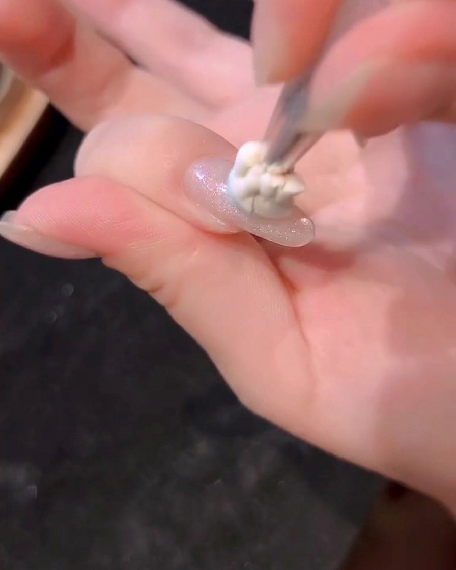 Une petite goutte de gel bleu appliquée au centre dun ongle avec un pinceau.