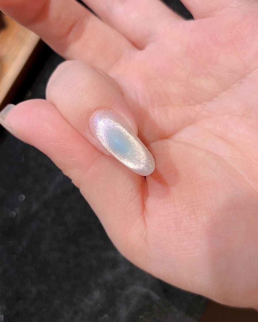 Gros plan dun ongle sous la lampe UV, montrant le gel bleu en cours de catalyse.