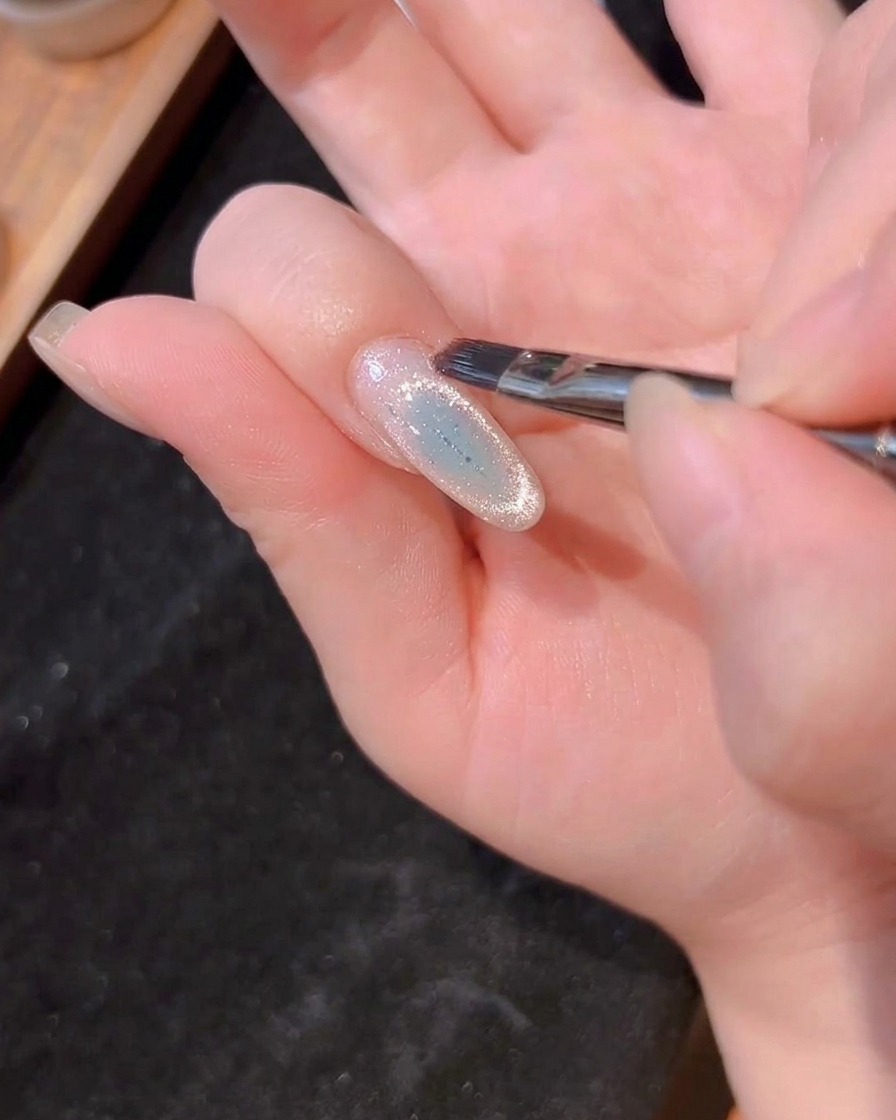 Un pinceau à ongles appliquant une fine couche de gel de construction transparent sur longle.