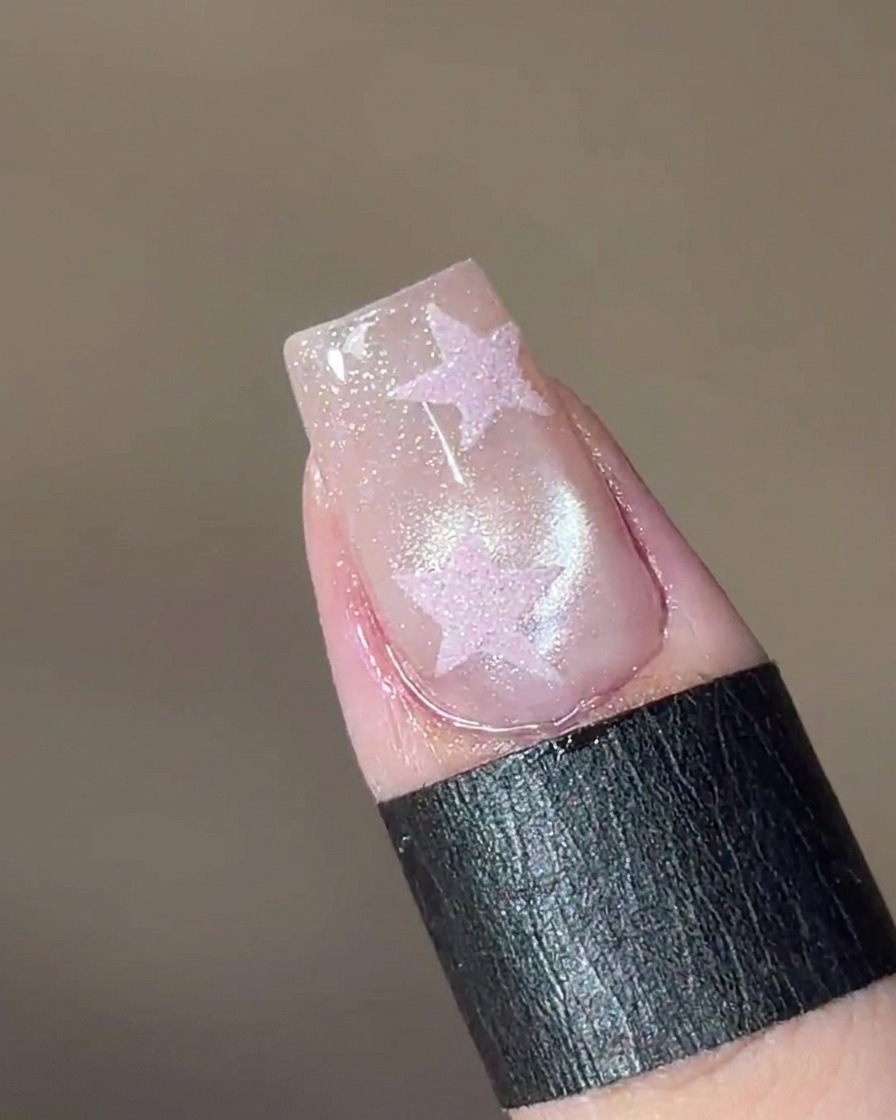 Un aimant maintenu au-dessus de longle, faisant apparaître un effet de perle de verre dans le gel.