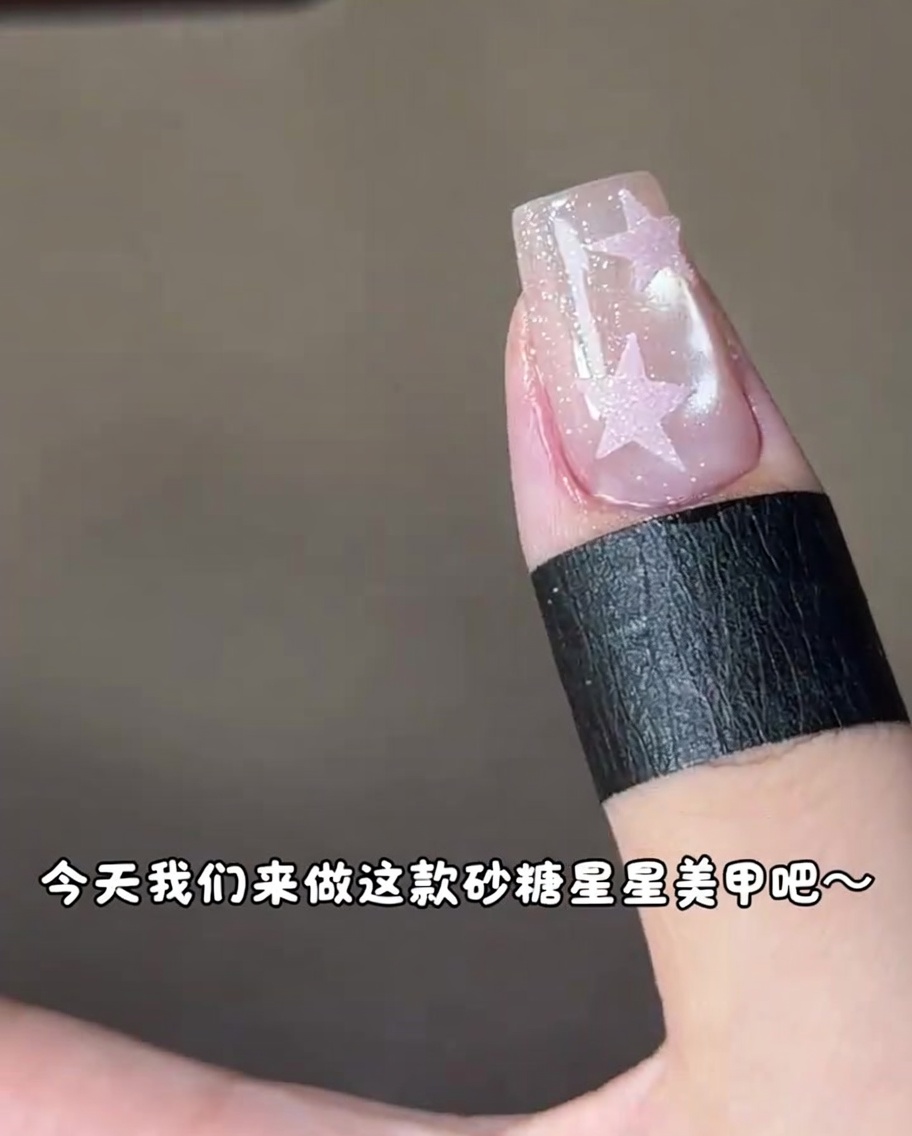 Un ongle avec une étoile rose en cours de catalysation sous une lampe UV.