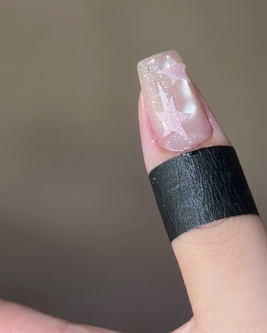 Poudre sugar rose saupoudrée sur une étoile couverte de top coat humide sur un ongle.