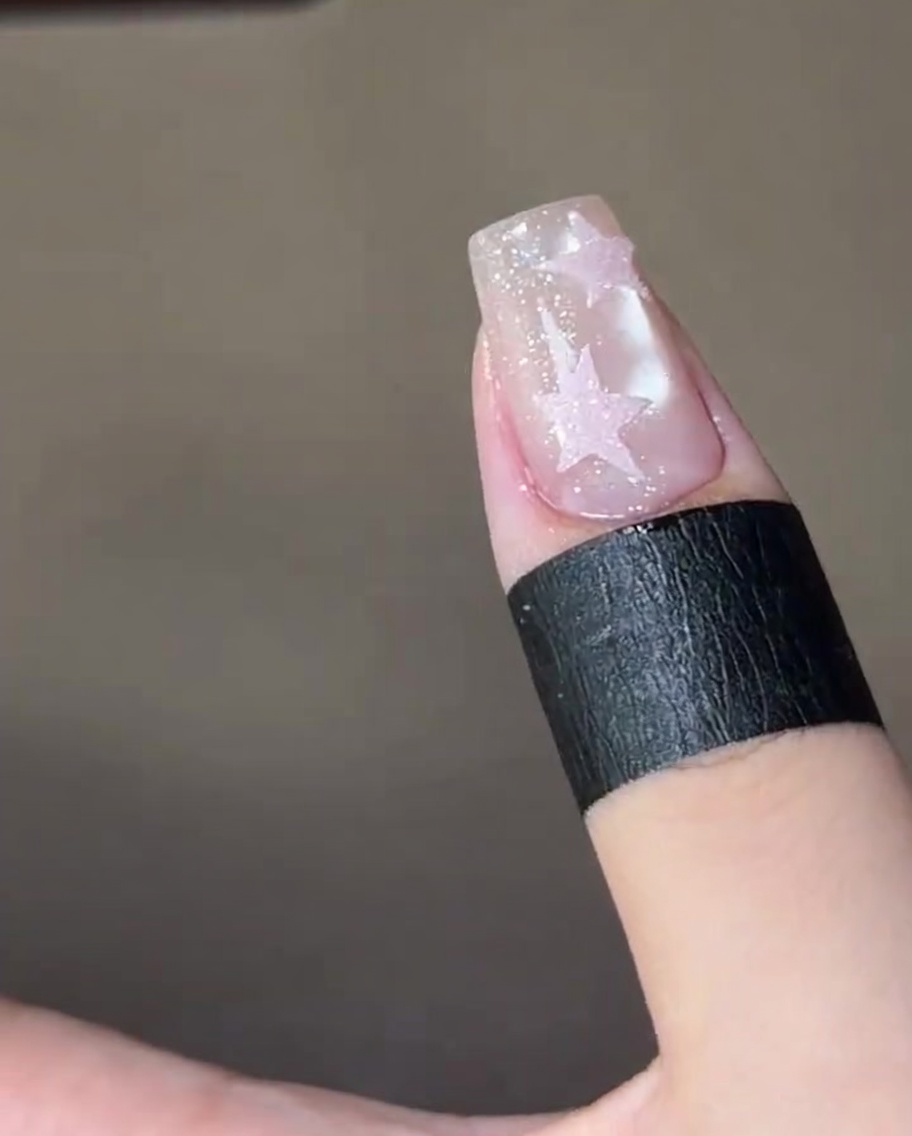 Un ongle fini avec deux étoiles roses texturées, catalysé à lintérieur dune lampe UV.