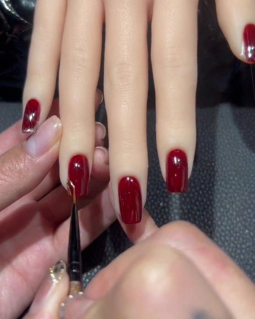Un pinceau liner fin prélevant une perle de vernis gel à paillettes or rose dense.