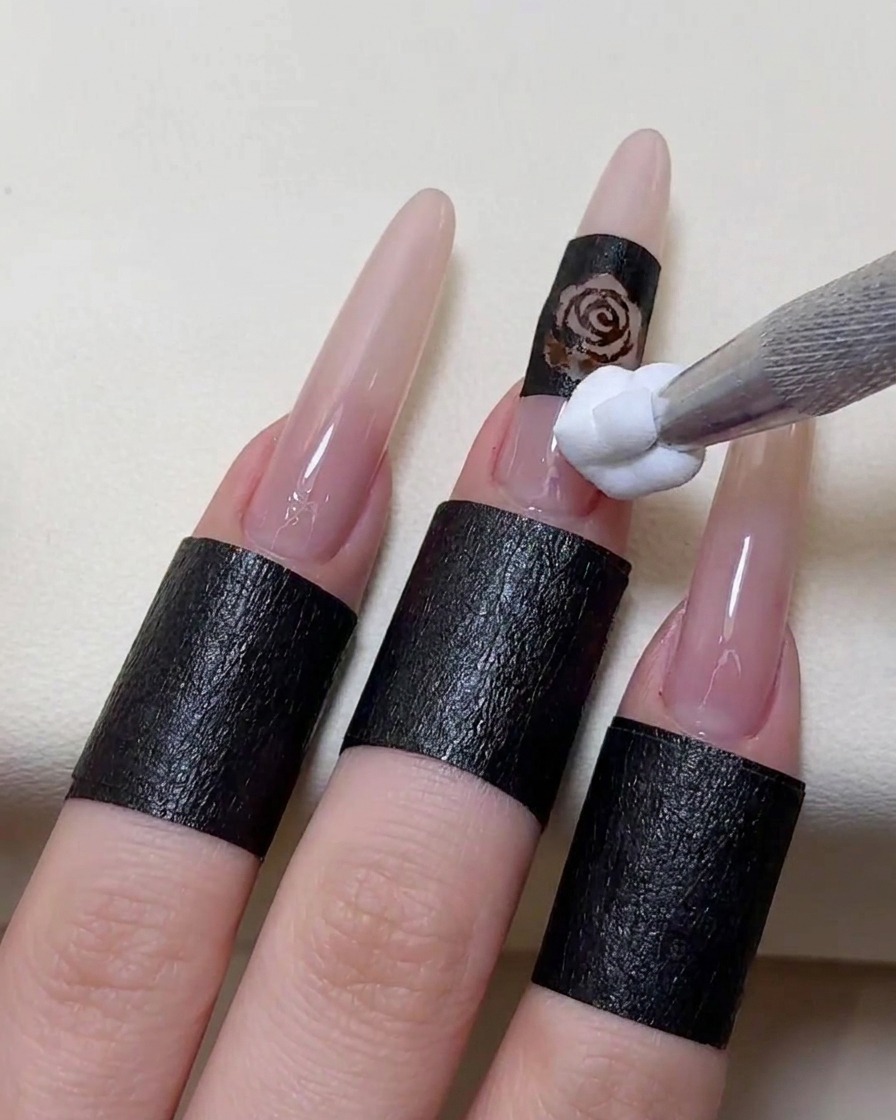 Un applicateur mousse tapotant du vernis gel blanc sur un pochoir placé sur un ongle.