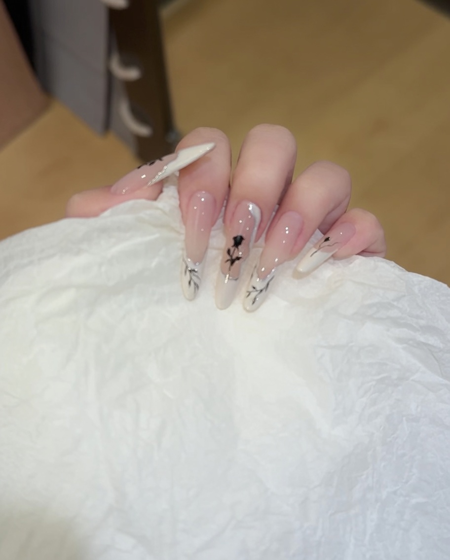 Gros plan dun pinceau appliquant du vernis blanc en forme de French manucure ondulée et irrégulière sur lextrémité dun ongle naturel.