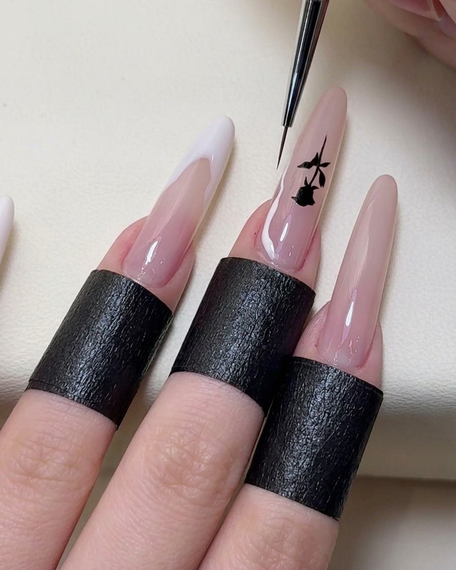 Un pinceau nail art fin dessinant des lignes de French manucure irrégulières en blanc sur le bout des ongles.