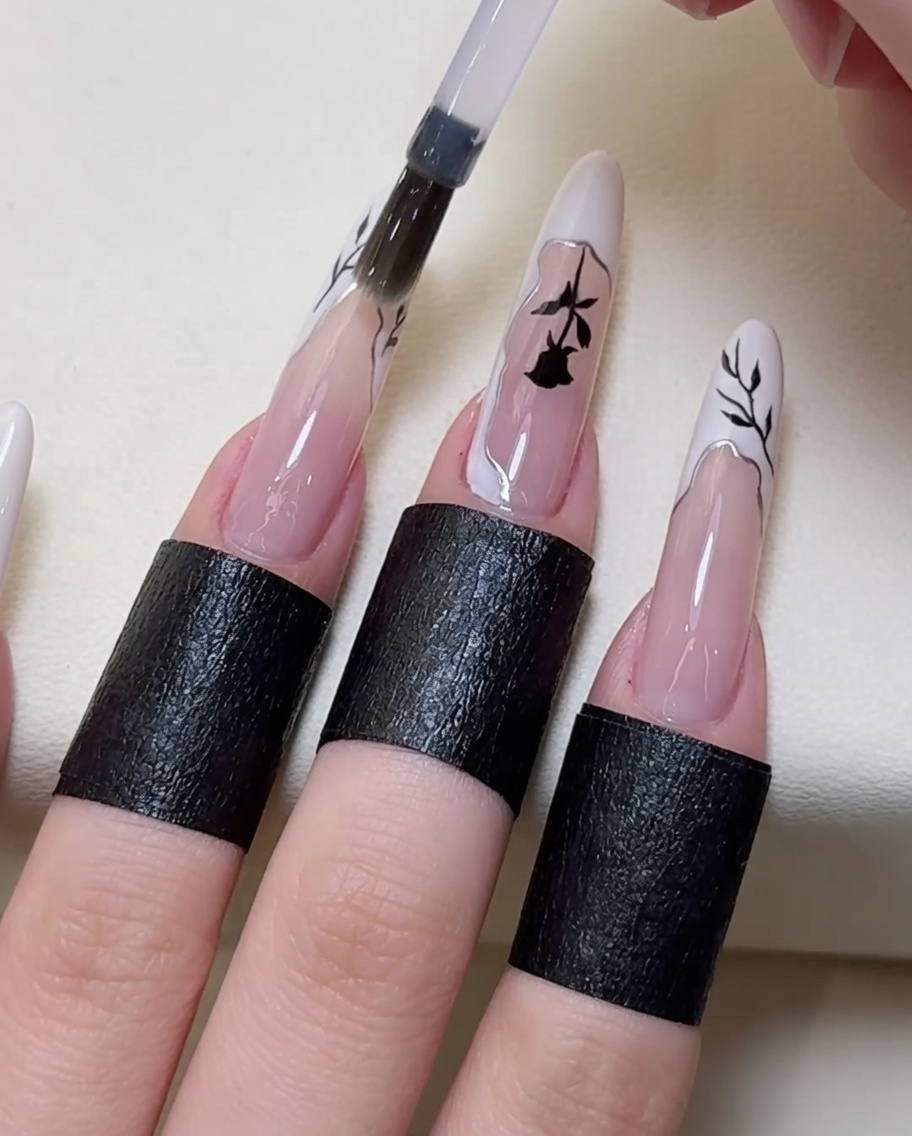 Un pinceau appliquant une couche de top coat transparent sur le nail art terminé.