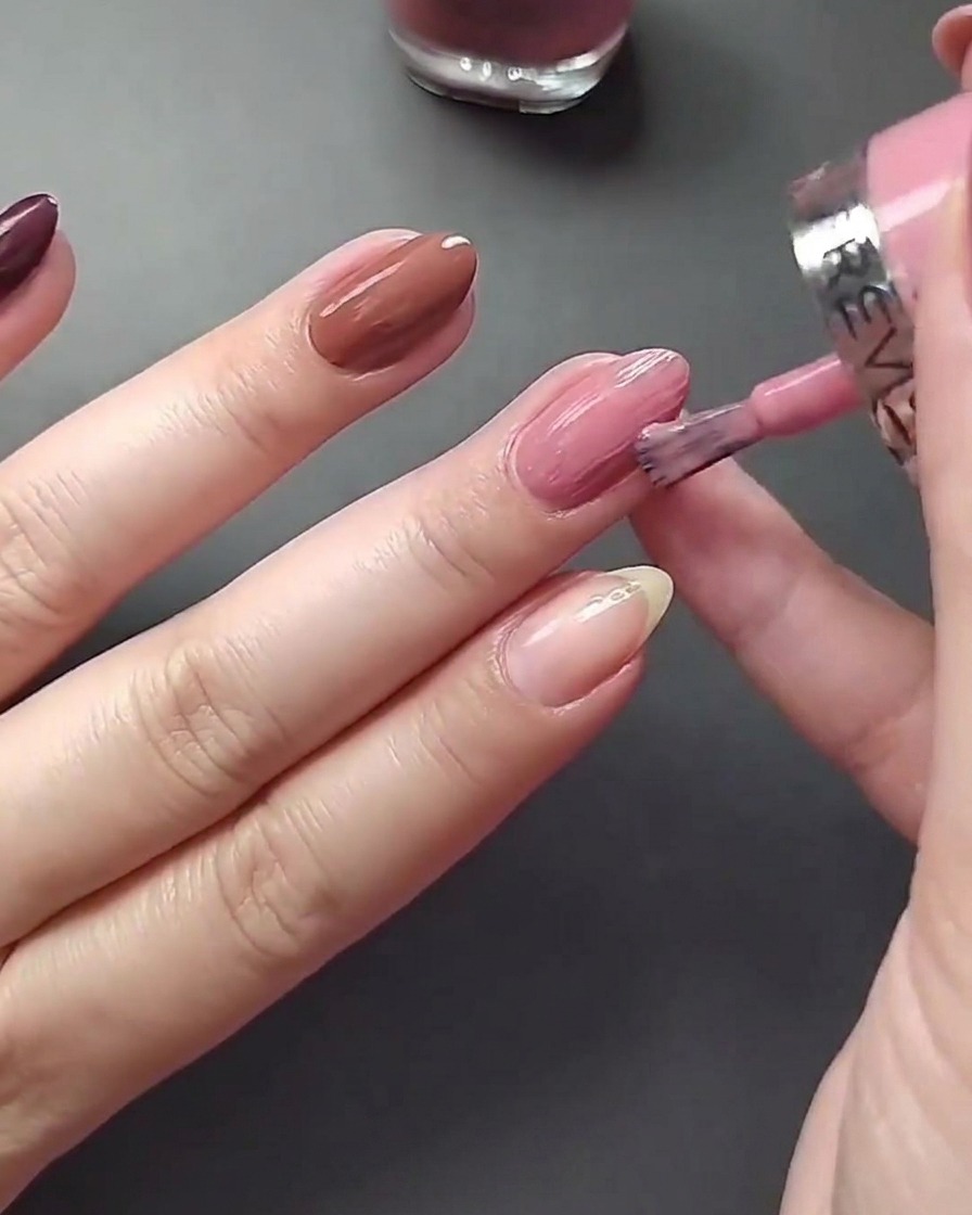 Gros plan de lapplication dun vernis nude clair sur le pouce.
