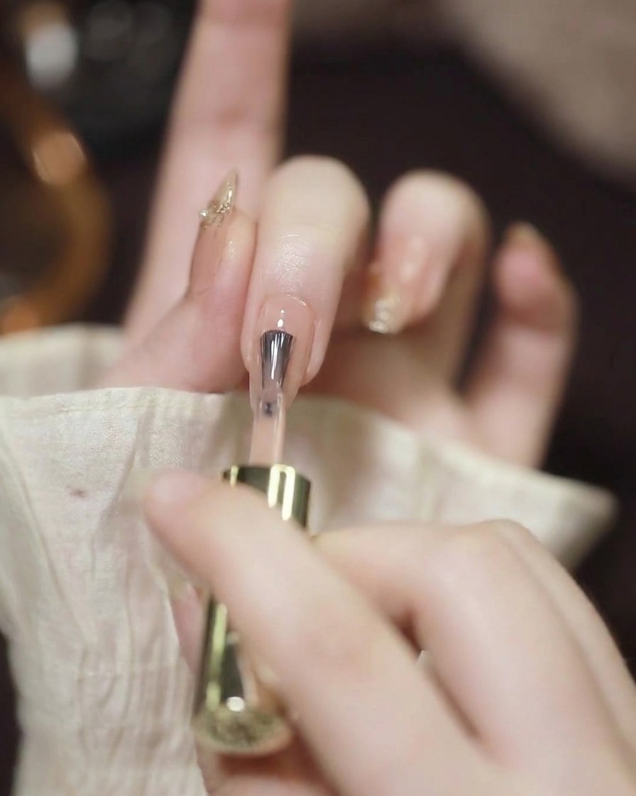 Gros plan dun pinceau à ongles appliquant un vernis gel nude transparent sur un ongle préparé et propre.