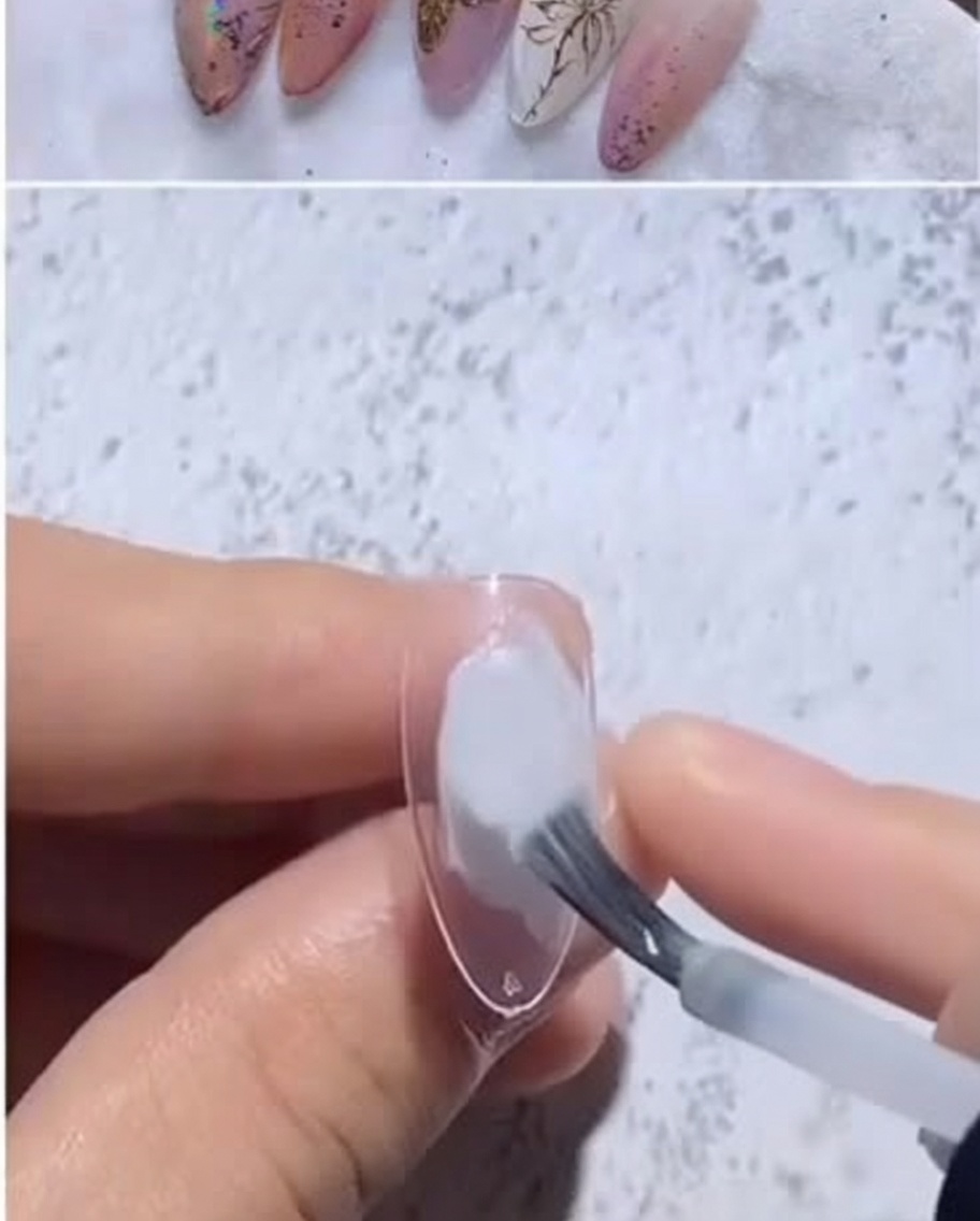 Gros plan dune capsule en amande recevant une goutte de vernis gel blanc laiteux au pinceau.
