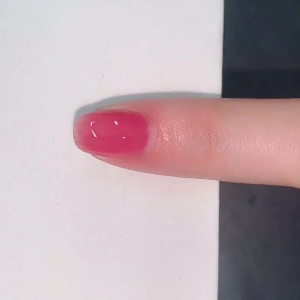 Un seul ongle recouvert dune couche brillante et translucide de vernis jelly rose.