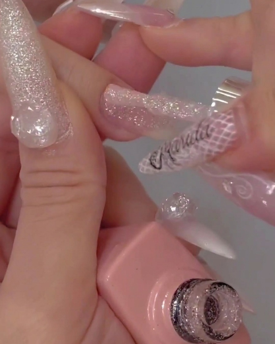 Pinceau de flacon de gel appliquant un top coat transparent sur un ongle pailleté texturé.