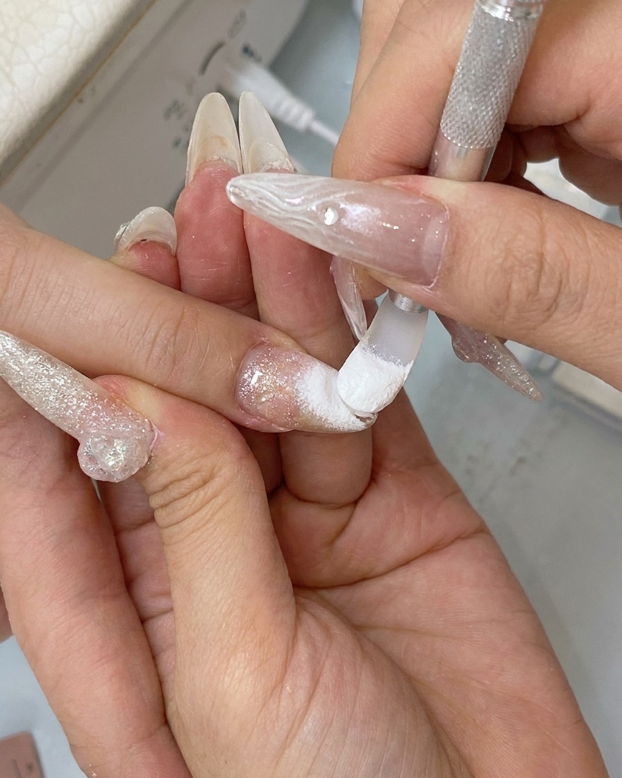 Un doigt frottant la surface de longle pour polir la poudre chrome jusquà obtenir un fini miroir réfléchissant.