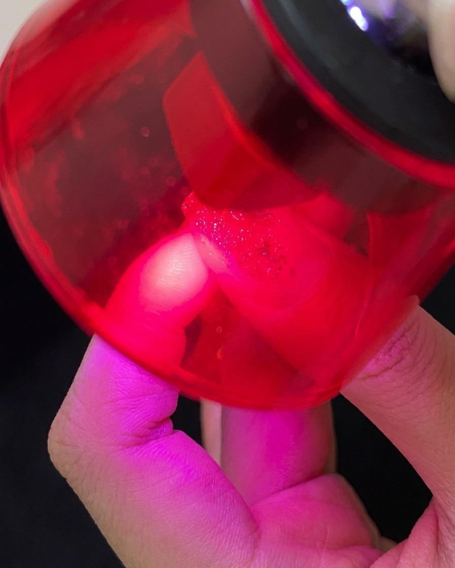 Un pinceau appliquant un top coat transparent brillant sur un ongle décoré.