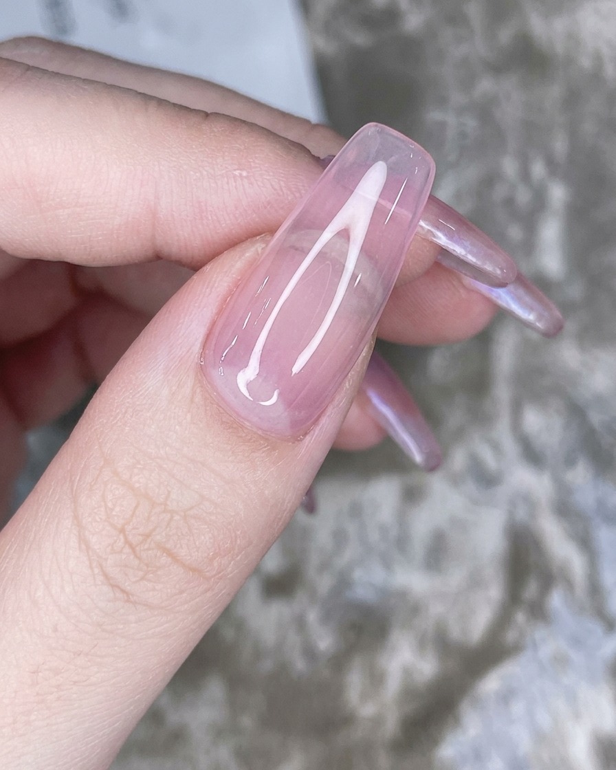 Un applicateur éponge tapotant de la poudre chrome irisée sur le bout de longle rose.