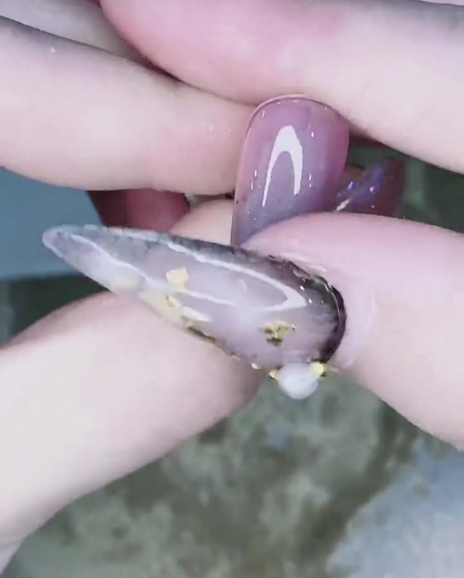 Un doigt estompant la poudre chrome de la pointe de longle vers le haut pour créer un dégradé.