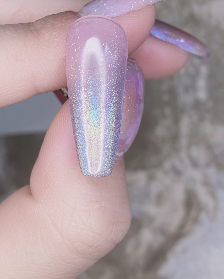 Un pinceau à ongles appliquant une couche transparente de gel de renforcement sur longle décoré au chrome.