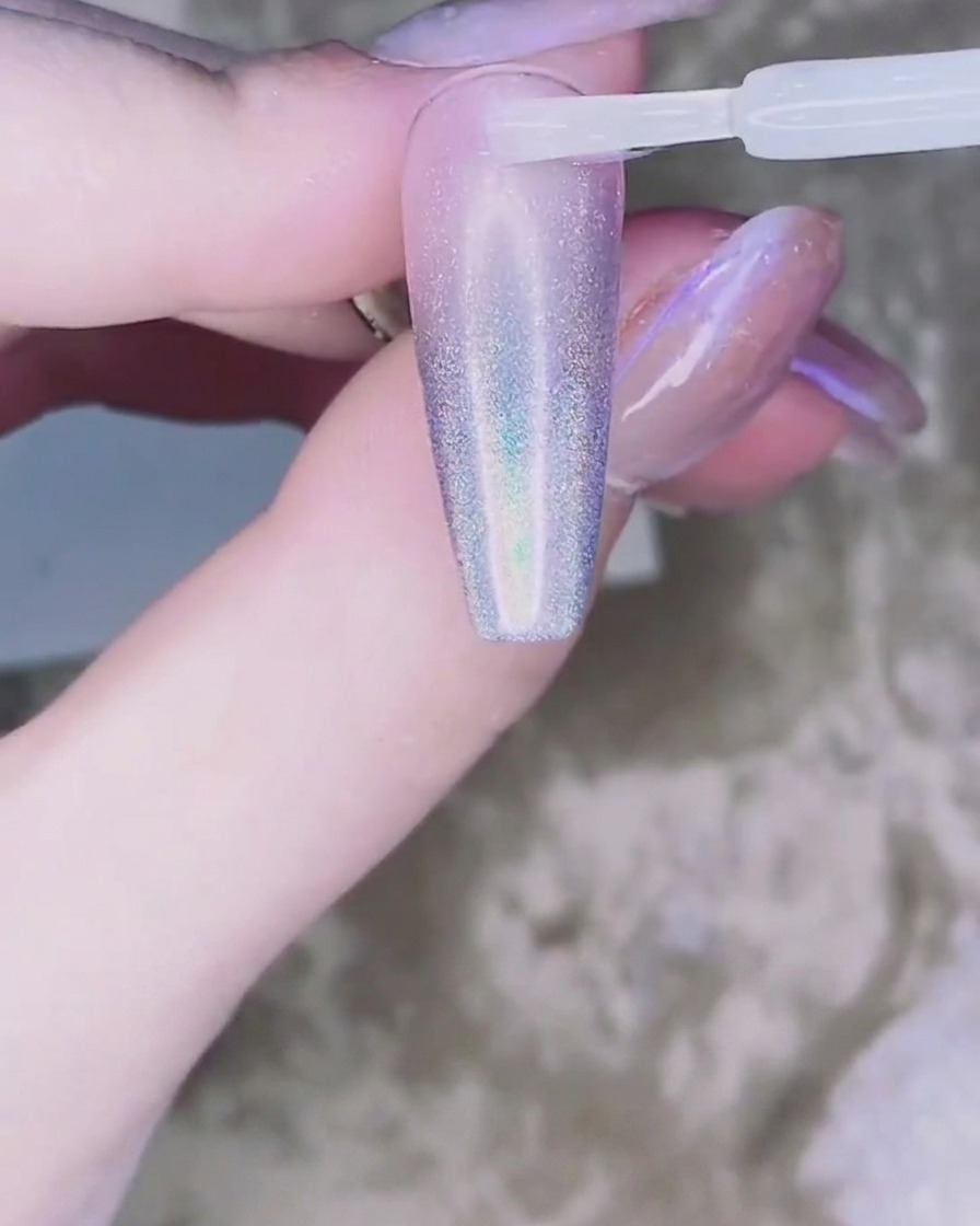 Une minuscule goutte de gel adhésif transparent placée au centre de longle.